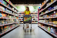 A woman walking with a shopping cart in a grocery store 